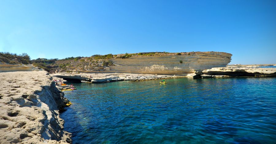 A goregous view of St.Peter's Pool showing crystal blue waters, the rocky beach and a deep blue sky.
